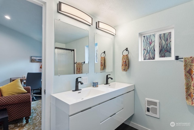 bathroom featuring a stall shower, a sink, heating unit, and double vanity