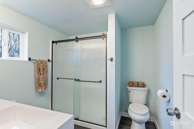 full bath featuring visible vents, toilet, a shower stall, wood finished floors, and baseboards