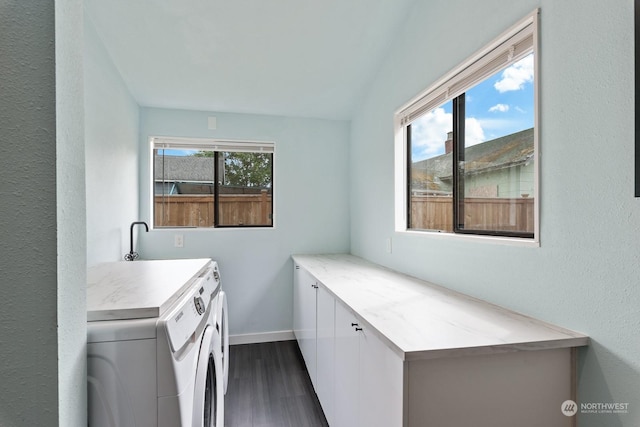 laundry room featuring dark wood-type flooring, washer and clothes dryer, cabinet space, and a healthy amount of sunlight