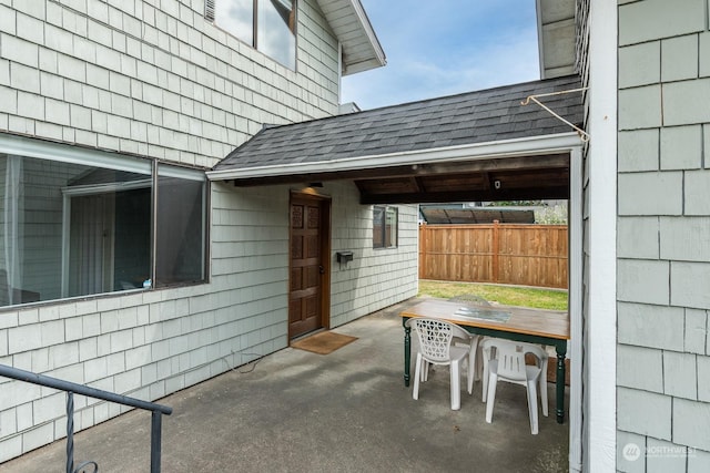 view of patio featuring fence, an attached carport, and outdoor dining space