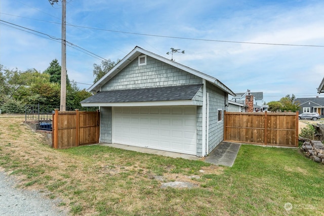 exterior space featuring an outbuilding, roof with shingles, a yard, fence, and a garage