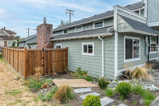 view of property exterior featuring fence and roof with shingles