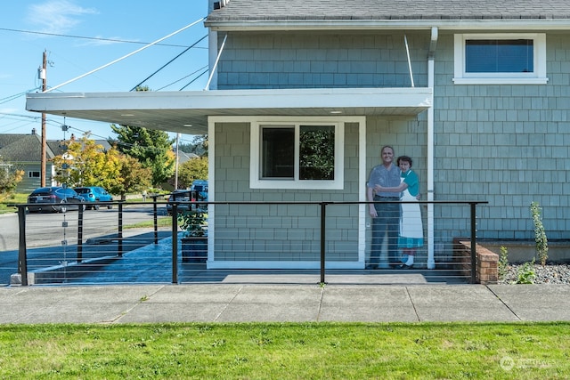 property entrance with a shingled roof and a carport