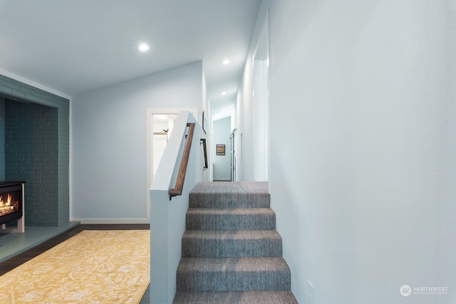 stairs with recessed lighting, a wood stove, vaulted ceiling, and wood finished floors