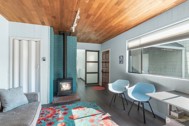 living area featuring a wood stove, wood ceiling, and wood finished floors