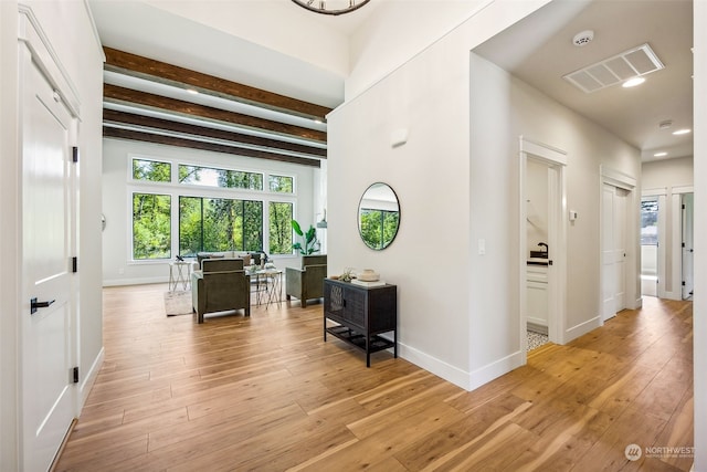 corridor with beamed ceiling and light hardwood / wood-style floors