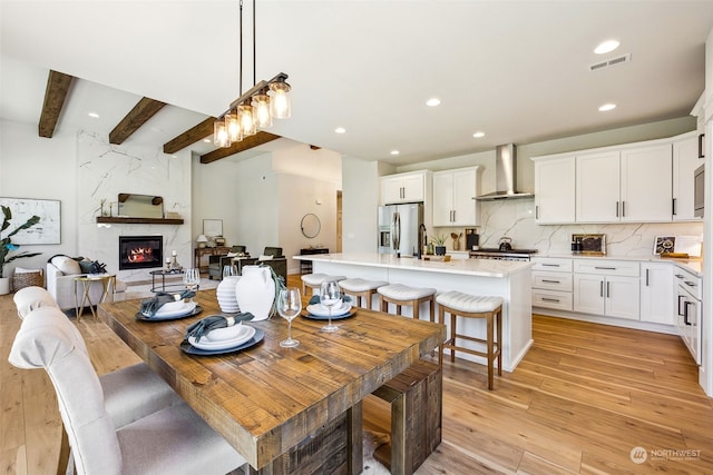 dining space featuring sink, light wood-type flooring, beam ceiling, and a fireplace