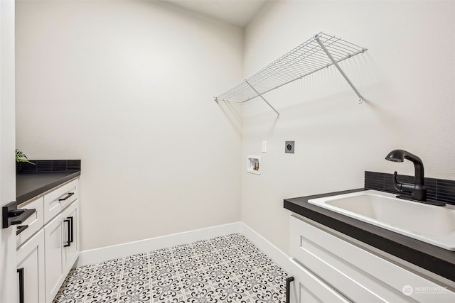 clothes washing area featuring a sink, baseboards, cabinet space, and washer hookup