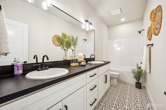 bathroom featuring a sink, washtub / shower combination, toilet, and double vanity