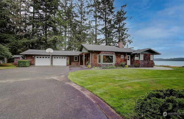 ranch-style house with a front yard, a garage, and a water view