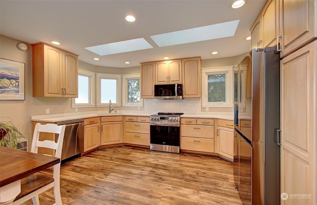 24424 Sandridge Rd, Ocean Park, WA 98640 - kitchen featuring stainless steel appliances, light brown cabinetry, a skylight, a sink, and recessed lighting