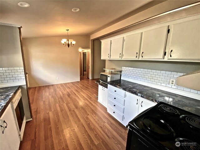 kitchen featuring electric range, decorative backsplash, an inviting chandelier, white cabinetry, and wood finished floors