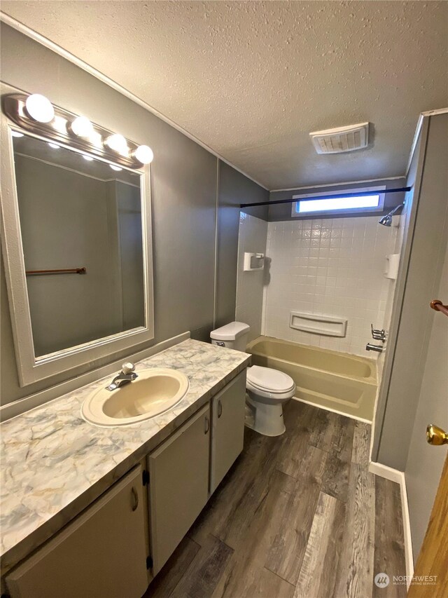 bathroom featuring visible vents, toilet, a textured ceiling, vanity, and wood finished floors