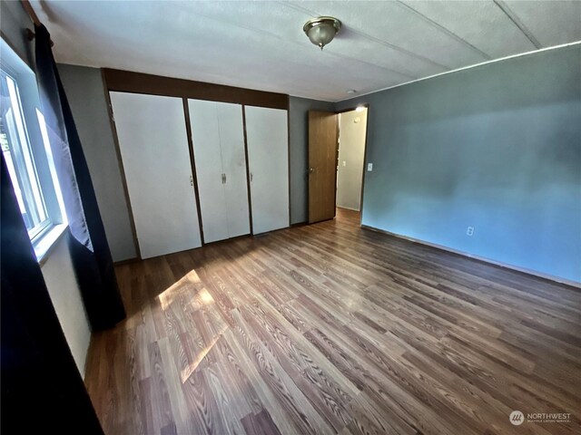 unfurnished bedroom with a closet, multiple windows, and wood finished floors