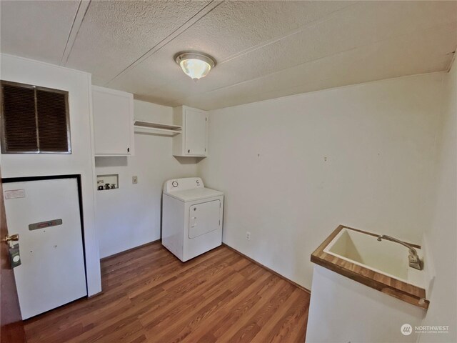 laundry area with a textured ceiling, wood finished floors, visible vents, cabinet space, and washer / dryer