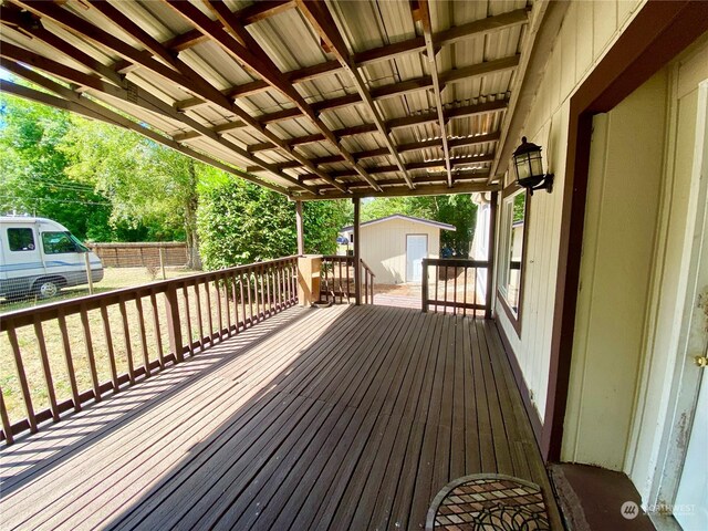 wooden terrace with an outbuilding, a shed, and fence