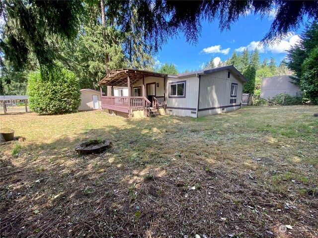 view of front of house with an outbuilding, a deck, crawl space, a shed, and a front yard