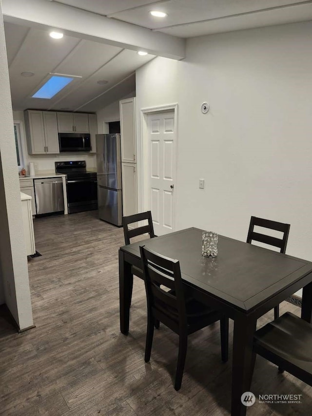 dining area featuring vaulted ceiling with skylight and dark wood-type flooring