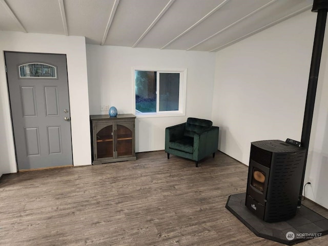 sitting room featuring beam ceiling, hardwood / wood-style floors, and a wood stove