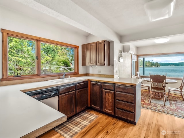 kitchen with light wood-type flooring, sink, kitchen peninsula, and dishwashing machine