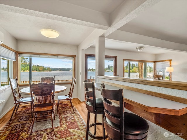 dining space with light hardwood / wood-style floors, a textured ceiling, and a water view