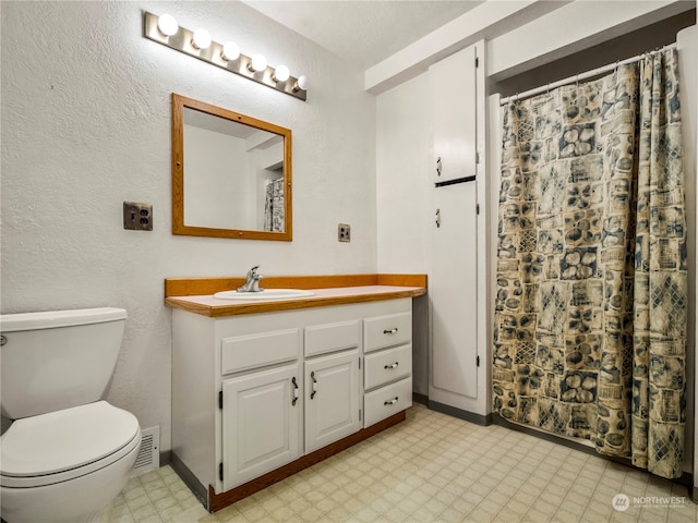 bathroom featuring tile patterned flooring, toilet, and vanity