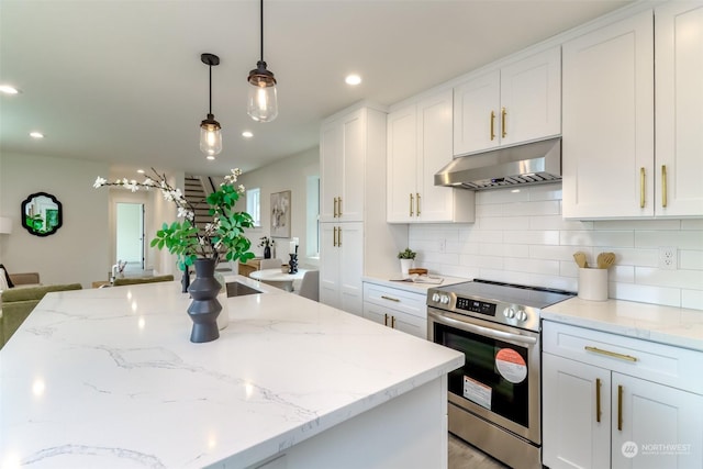 kitchen with under cabinet range hood, stainless steel electric range, white cabinets, and decorative light fixtures