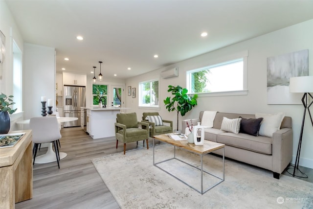 living area featuring light wood-type flooring, a wall mounted air conditioner, and recessed lighting