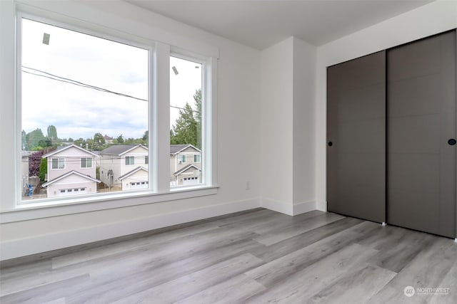 unfurnished bedroom with light wood-style floors, baseboards, and a closet