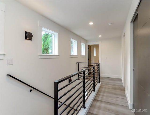 interior space featuring light wood-style floors, recessed lighting, baseboards, and an upstairs landing