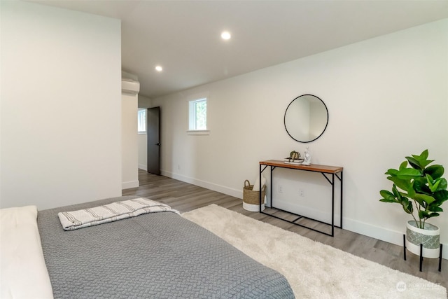 unfurnished bedroom with baseboards, light wood-type flooring, a wall unit AC, and recessed lighting