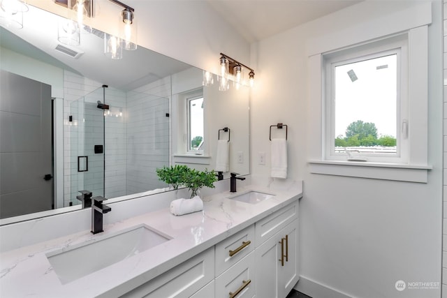 full bath with a stall shower, a healthy amount of sunlight, visible vents, and a sink