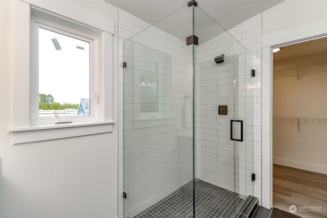 bathroom featuring a stall shower, a spacious closet, baseboards, and wood finished floors