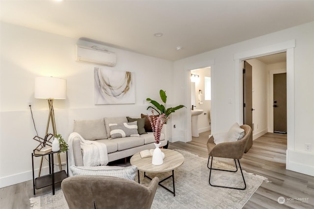 living area with light wood-type flooring, an AC wall unit, and baseboards