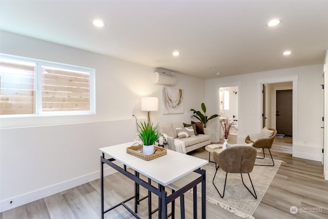 living area featuring light wood-type flooring, recessed lighting, baseboards, and a wall mounted AC