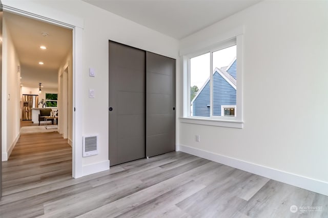 unfurnished bedroom with light wood-style flooring, baseboards, a closet, and recessed lighting