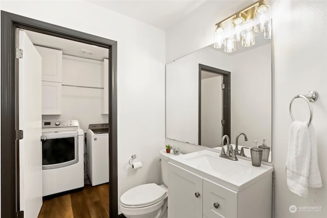 bathroom featuring washer and dryer, vanity, toilet, and hardwood / wood-style flooring