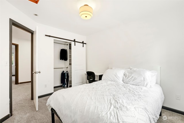 carpeted bedroom with a barn door and a closet