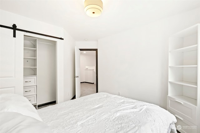 bedroom featuring light carpet, a barn door, and a closet