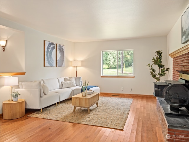 living room featuring light hardwood / wood-style flooring and a brick fireplace