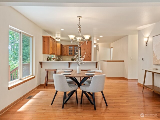 dining area with light hardwood / wood-style floors and an inviting chandelier