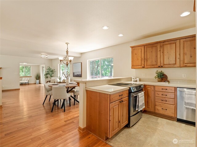 kitchen with light wood-type flooring, appliances with stainless steel finishes, a chandelier, and a healthy amount of sunlight