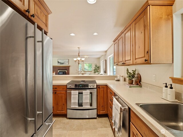 kitchen featuring appliances with stainless steel finishes, sink, kitchen peninsula, a notable chandelier, and light tile patterned flooring