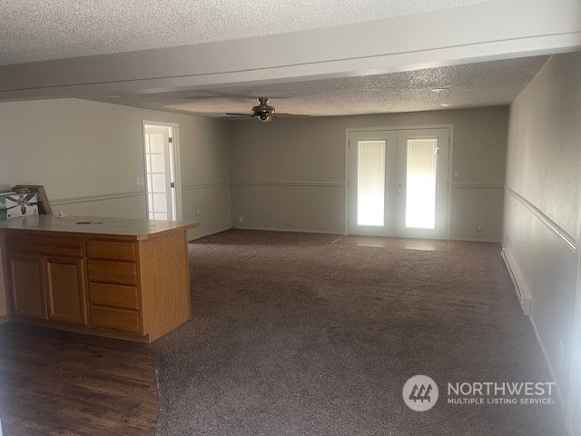 spare room featuring ceiling fan, dark hardwood / wood-style floors, french doors, and a textured ceiling