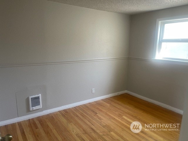 empty room featuring a textured ceiling and light hardwood / wood-style flooring