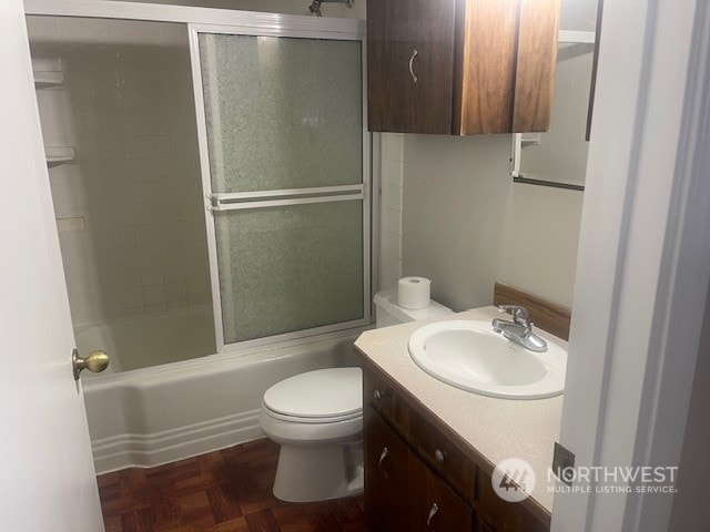 full bathroom with shower / bath combination with glass door, toilet, parquet flooring, and vanity