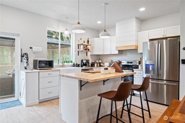 kitchen featuring white cabinetry, appliances with stainless steel finishes, light hardwood / wood-style flooring, and a kitchen island