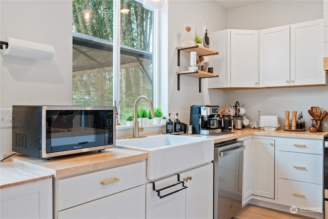 kitchen featuring wooden counters, sink, light hardwood / wood-style flooring, white cabinetry, and stainless steel appliances