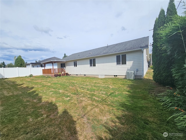 rear view of property featuring a wooden deck, central air condition unit, and a yard