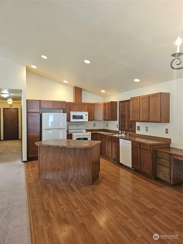 kitchen with a center island, sink, high vaulted ceiling, dark hardwood / wood-style flooring, and white appliances